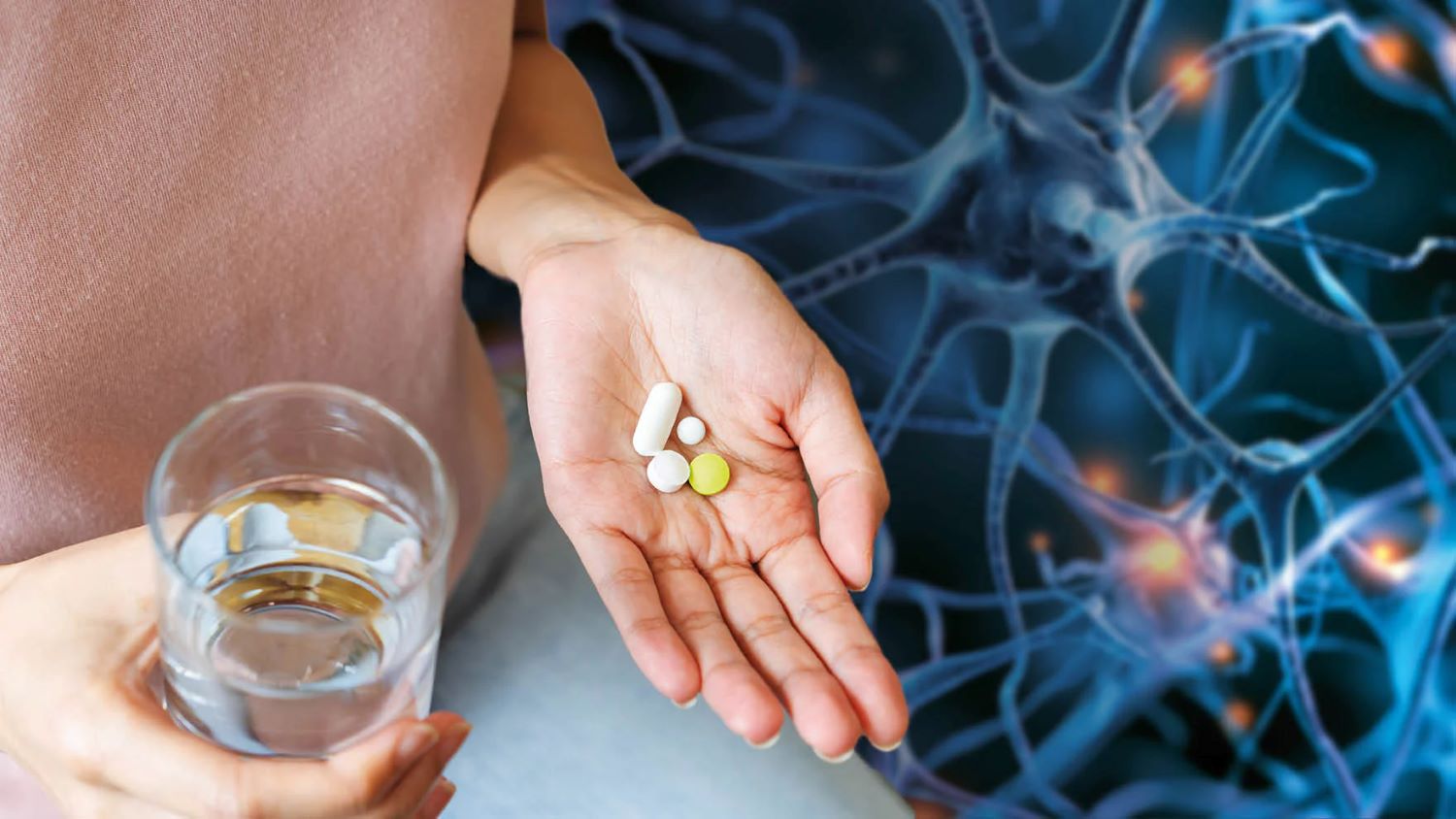 Pillole nella mano di una persona, con un bicchiere d'acqua nell'altra.