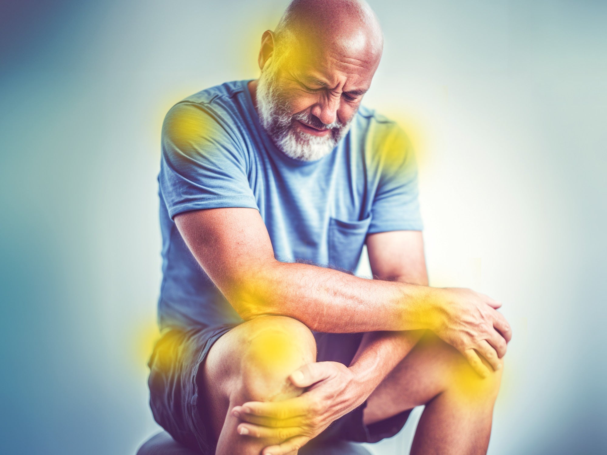 Un homme barbu en t-shirt bleu est assis, se tenant la jambe avec une expression de douleur. Des lumières jaunes autour de ses genoux, bras et épaules symbolisent la douleur ou l'inflammation articulaire/nerveuse.